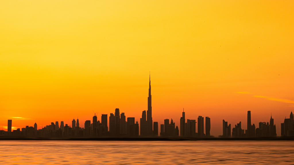 Skyline di Dubai con il Burj Khalifa illuminato al tramonto e grattacieli riflessi sull’acqua