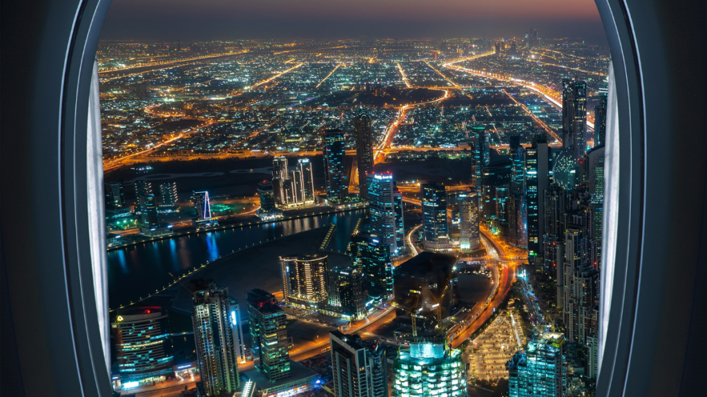 Valigia e passaporto con vista su Dubai dall’aereo, simbolo di un viaggio a Dubai