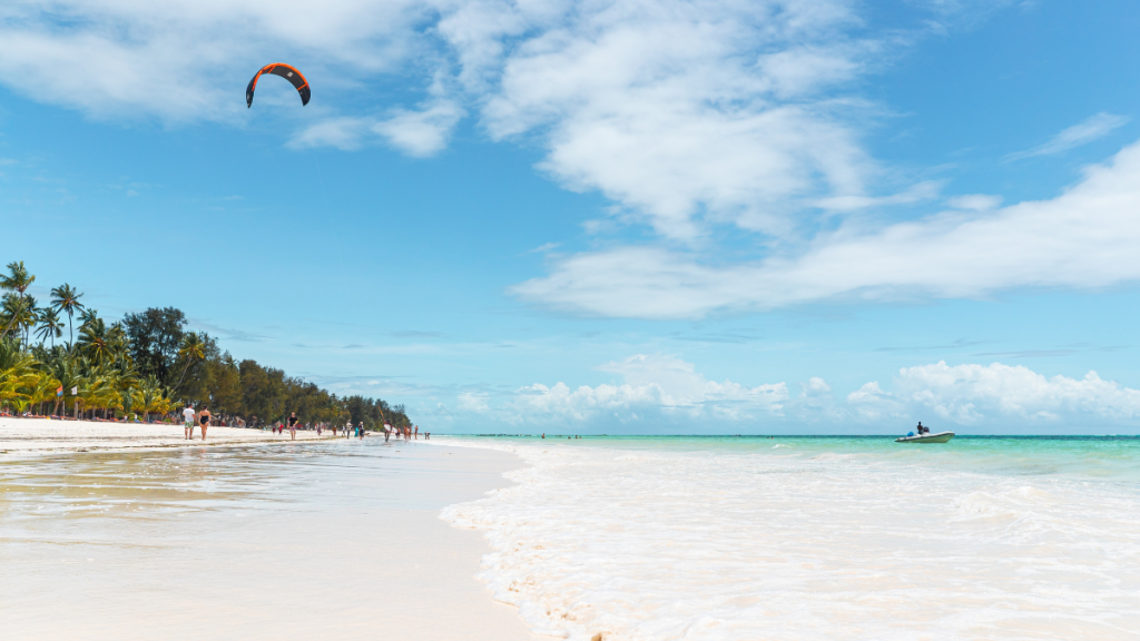 Lunga spiaggia di Paje a Zanzibar con bassa marea, persone che camminano sulla sabbia e kite in volo