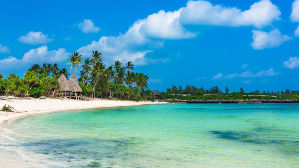 Spiaggia bianca di Zanzibar con mare turchese, palme e dhow tradizionale sullo sfondo